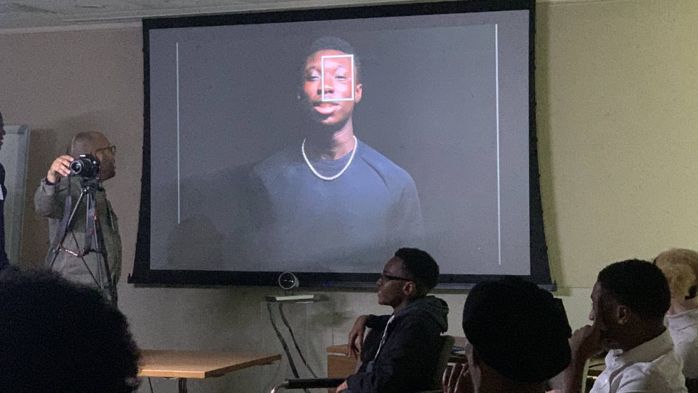 Picture of student being photographed in a workshop and projected onto a screen