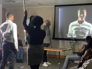 Student being projected onto a screen using a camera with other students helping